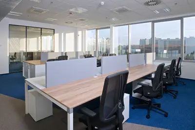 Součástí změny byl přesun trvalých pracovišť k oknům. Různé barevné kombinace desek stolů pomáhají rozbít fádní dojem z prostor